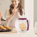 Distributeur de pâte rempli de pâte sur un plan de travail à côté de muffins