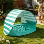 Tente de plage pop-up rayée turquoise et blanc avec pataugeoire sur une pelouse un jour ensoleillé