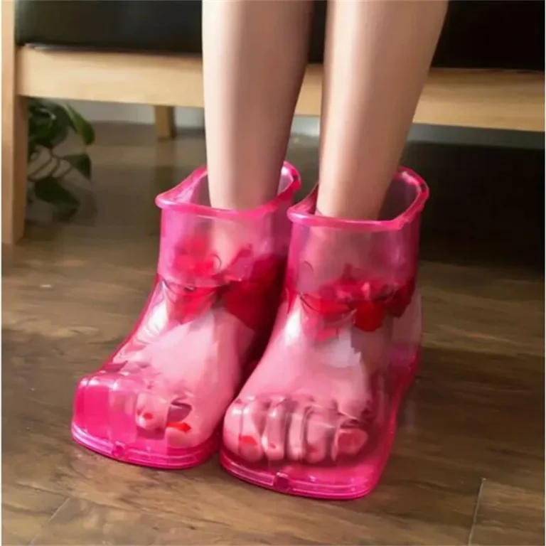 Chaussons de bain de pieds roses avec pétales de rose portés à la maison sur un parquet