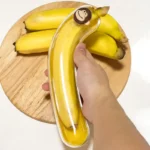 Boîte à banane transparente avec bouchon singe tenue au-dessus de bananes sur une planche en bois
