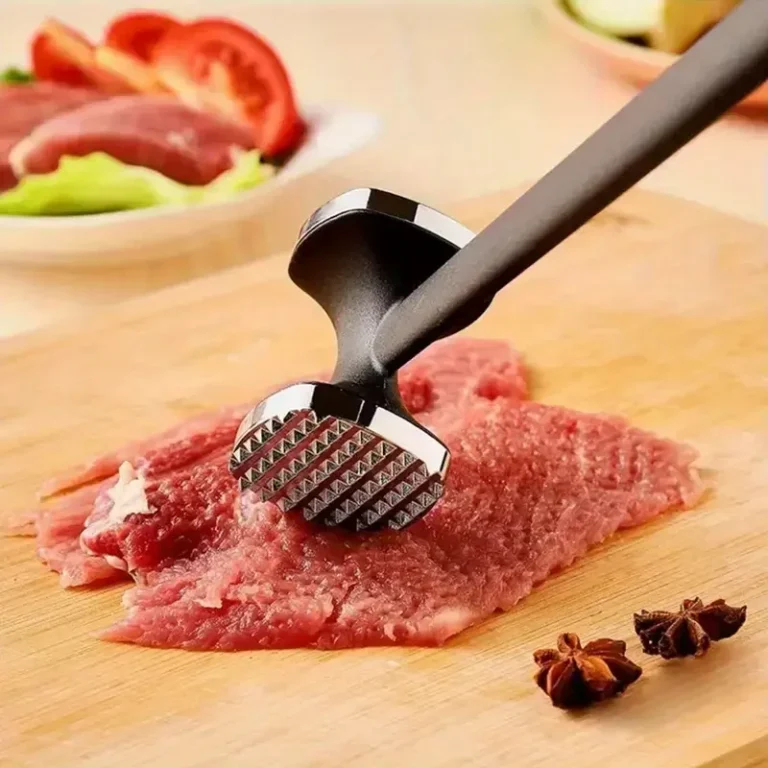 Attendrisseur à viande sur de la viande crue sur une planche à découper en bois