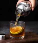 Shaker à cocktail en acier inoxydable versant une boisson sur de la glace