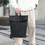 Sac à dos noir à fermeture enroulable porté à la main sur des marches en ville